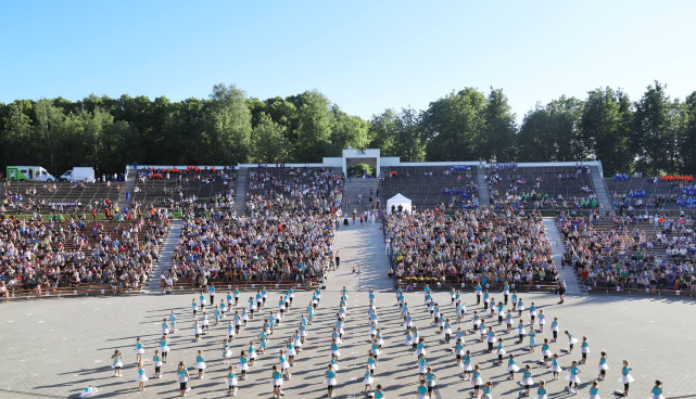 Tartu Võimlemispidu laululaval, mis on tehtud kaare alt vaatega publiku poole. Ees on näha palju lapsi tantsimas ja ka publikut on väga palju. 