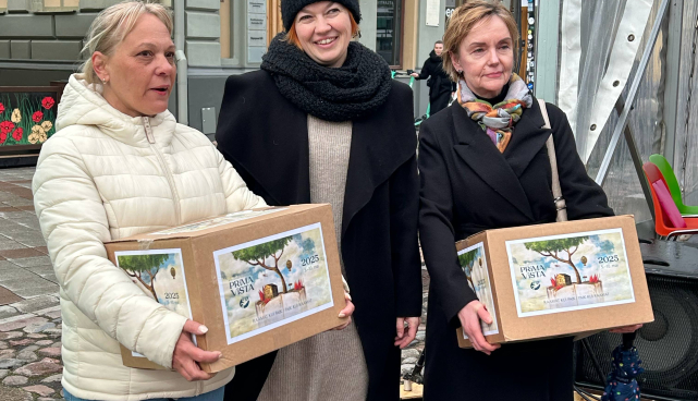 Kolm naisterahvast seisavad raekoja platsil ja kahel neist on käes pappkastid 