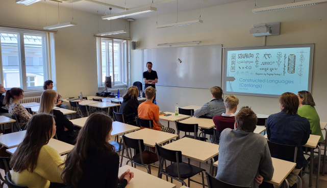 TÜ eesti ja üldkeeleteaduse instituudi doktorant Jesse Holmes lingvistikaolümpiaadi lõppvoorus õpilastele tehiskeelte loengut pidamas. Foto: Miina Norvik.
